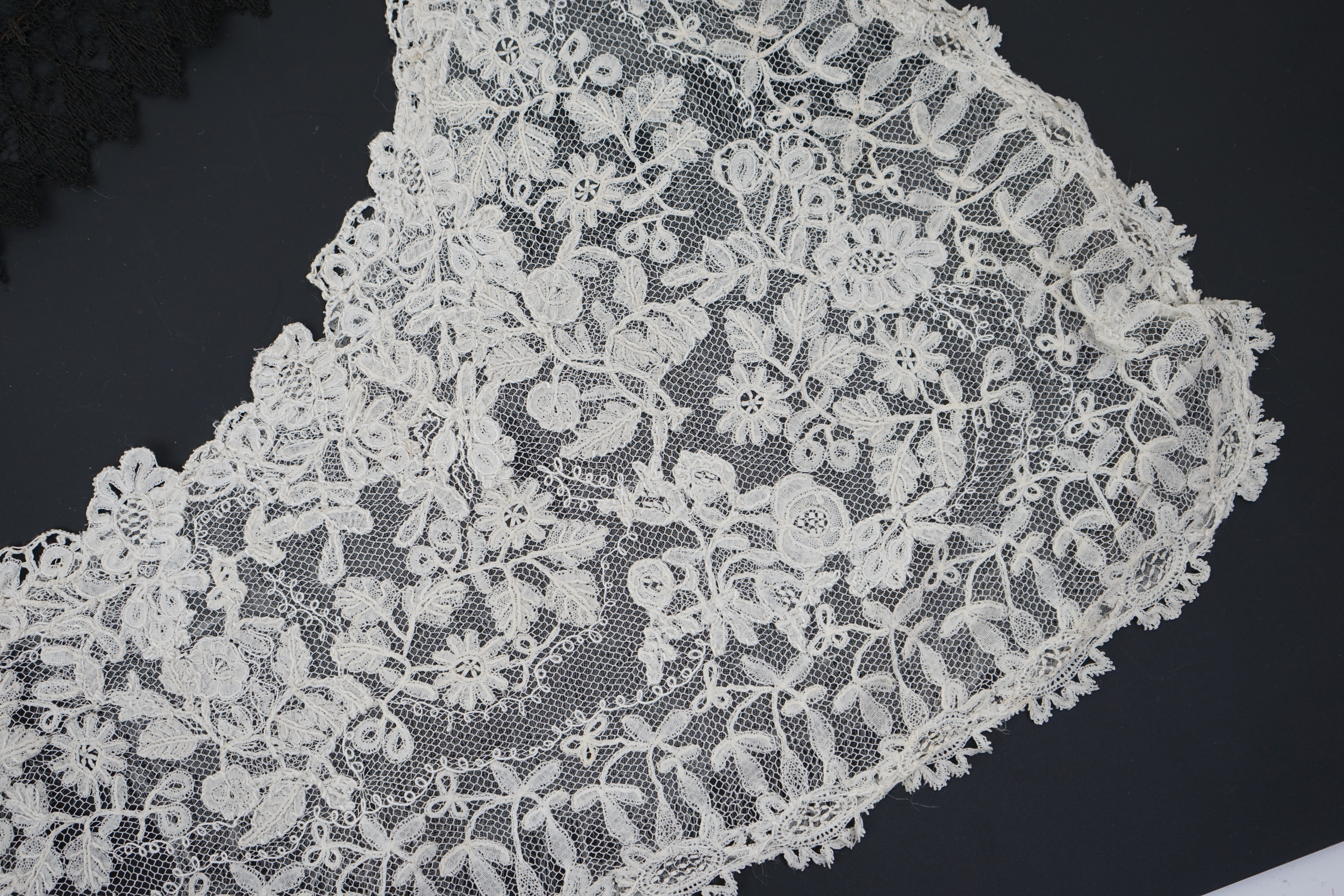 A small collection of late 19th century laces including a cream Brussels bobbin lace collar appliquéd on to net and two similar Brussels bobbin lace lappets, a pair of cream Honiton bobbin lace cuffs and a black lace fal